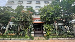A multi-story hotel with a central entrance, surrounded by lush greenery and a well-maintained garden. - DACO Hotel (Siem Reap)