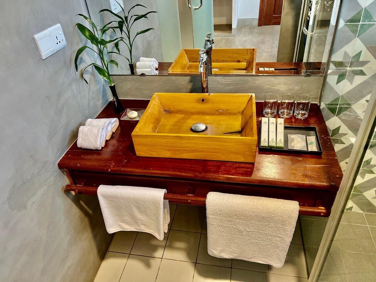 A wooden vanity with a rectangular sink, a mirror, and a tray with toiletries.
