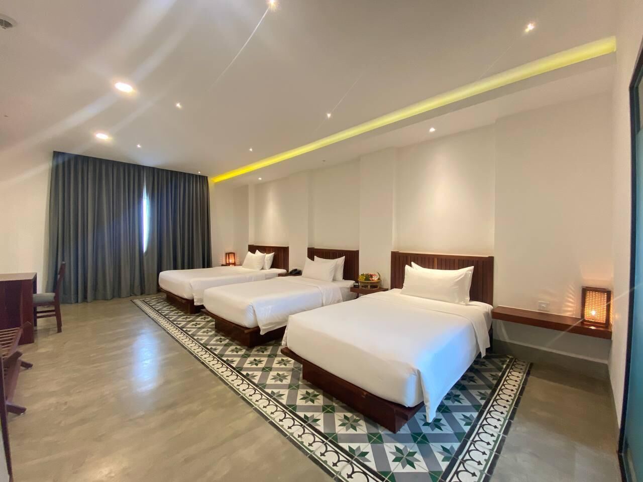 Een hotelkamer met drie eenpersoonsbedden, een bureau en een stoel.