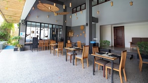 A modern restaurant with wooden tables and chairs, hanging pendant lights, and a mix of indoor and outdoor seating. - DACO Hotel (Siem Reap)