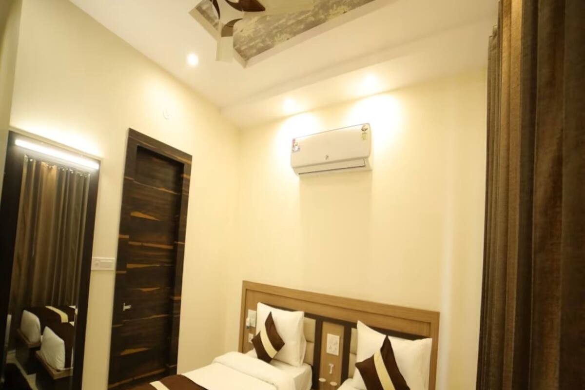 A hotel room with two beds, a ceiling fan, an air conditioning unit, and a mirror.