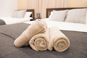 A neatly made bed with two rolled towels and a grey blanket. - tycq (Osaka)