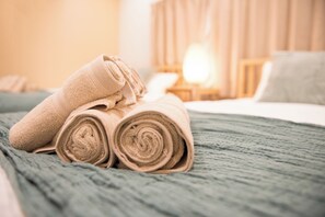 A neatly made bed with rolled towels and a green blanket. - tycq (Osaka)