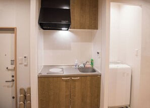 A compact kitchen with a stainless steel countertop, a built-in oven, and a small sink. - tycq (Osaka)