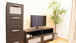Un soggiorno moderno con una TV a schermo piatto su un mobile in legno, una pianta in vaso e un'intera parete contenitore con cassetti.