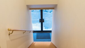 Una scala in legno conduce a una porta da cui si vede un paesaggio innevato.
