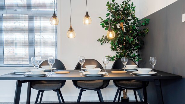 A dining area with a table set for four, three hanging pendant lights, and a large green plant on the wall. - City Centre 3-Bed Apartment – Sleeps up to 8 guests, with NCP car park next door (pay for parking). Walking distance to the Mayflower Theatre, shops, and transport. Ideal for families, groups, or business stays. (Southampton)
