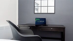 A hotel room with a bed, a desk with a laptop, a chair, and a window with blinds. - City Centre 3-Bed Apartment – Sleeps up to 8 guests, with NCP car park next door (pay for parking). Walking distance to the Mayflower Theatre, shops, and transport. Ideal for families, groups, or business stays. (Southampton)