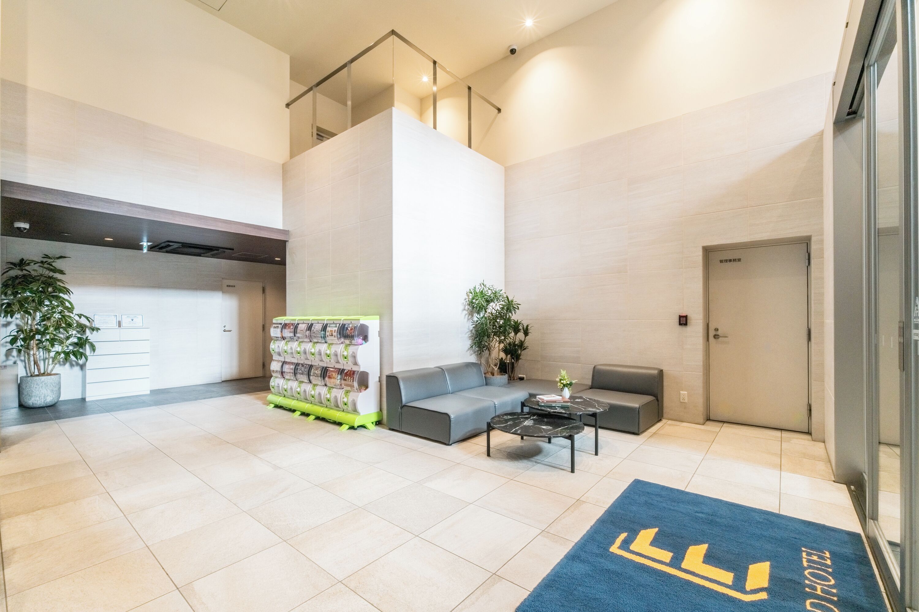 A modern hotel lobby with a reception desk, seating area, and a staircase.