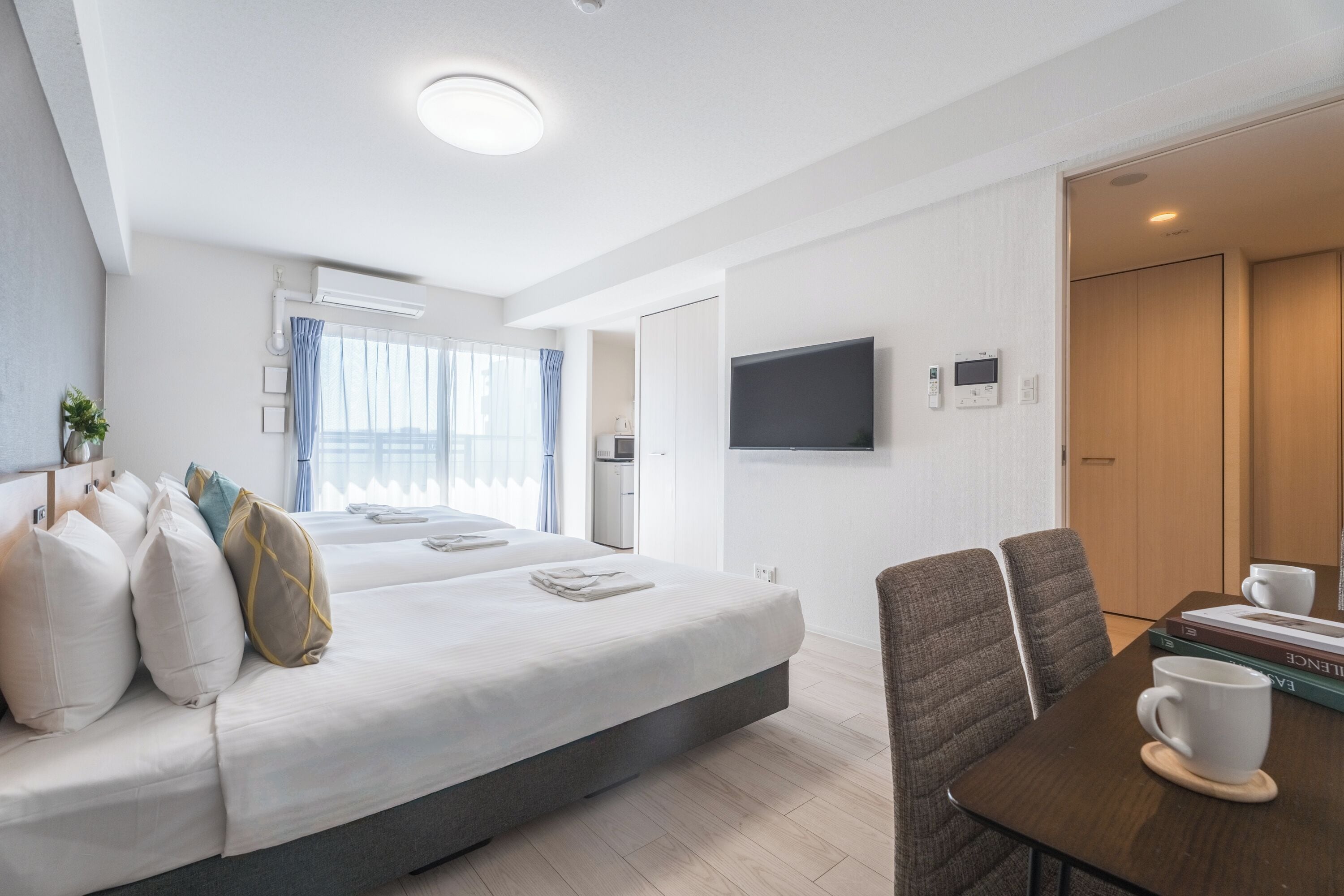 Ein modernes Hotelzimmer mit einem großen Bett, einem Fernseher, einem Couchtisch und einem Essbereich.