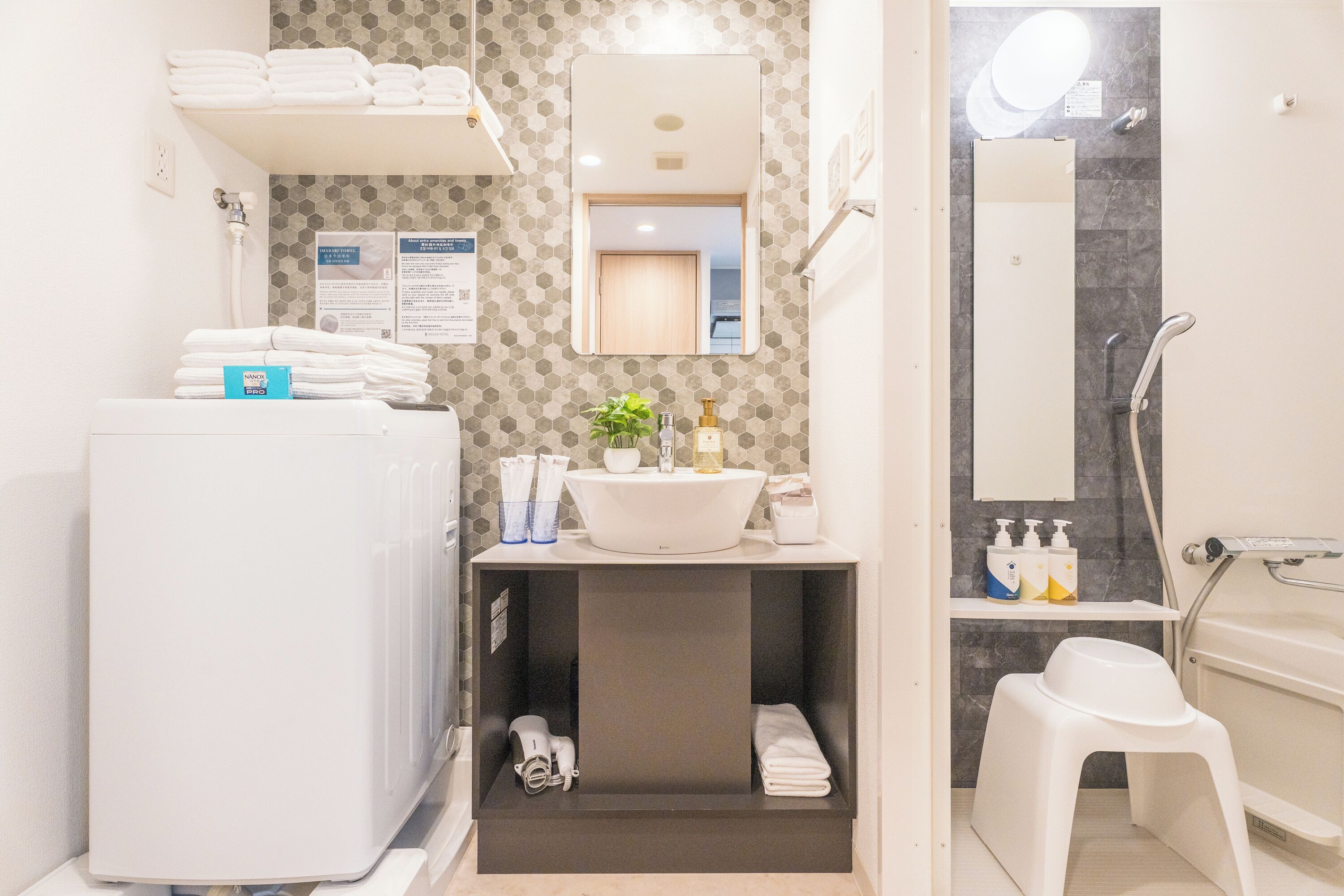 Un bagno moderno con un lavandino bianco, uno specchio sopra e una zona doccia.