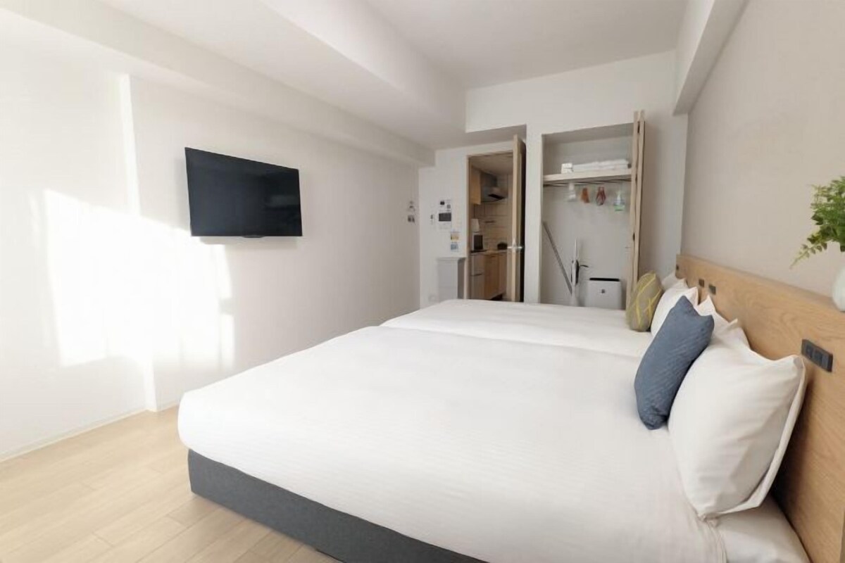 Quarto moderno com uma cama grande, televisão de tela plana na parede e cabeceira de madeira.