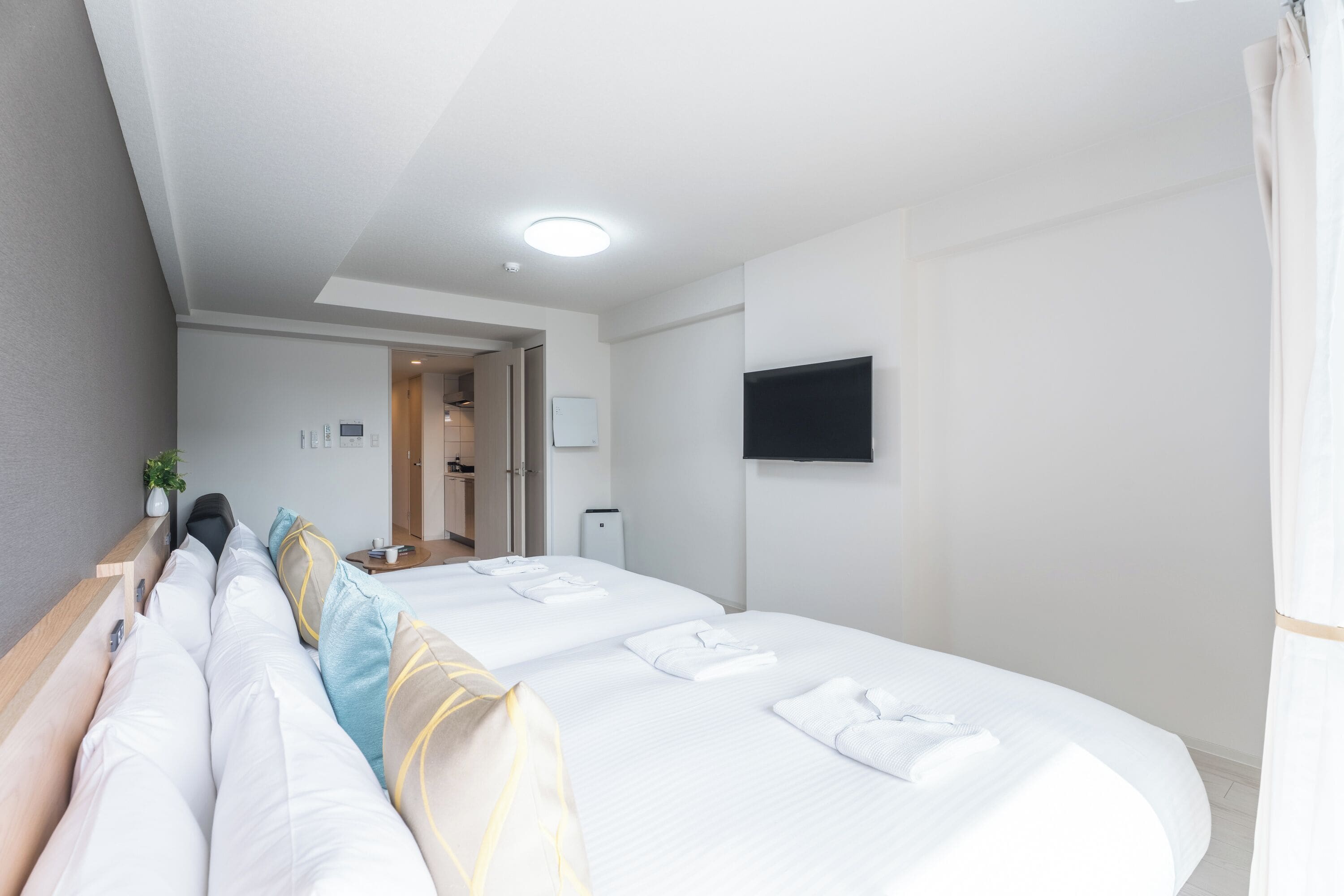 Une chambre d’hôtel avec deux lits, un téléviseur à écran plat fixé au mur et une porte donnant accès à la salle de bain.