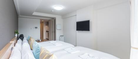 A hotel room with two beds, a flat-screen TV mounted on the wall, and a door leading to a bathroom.