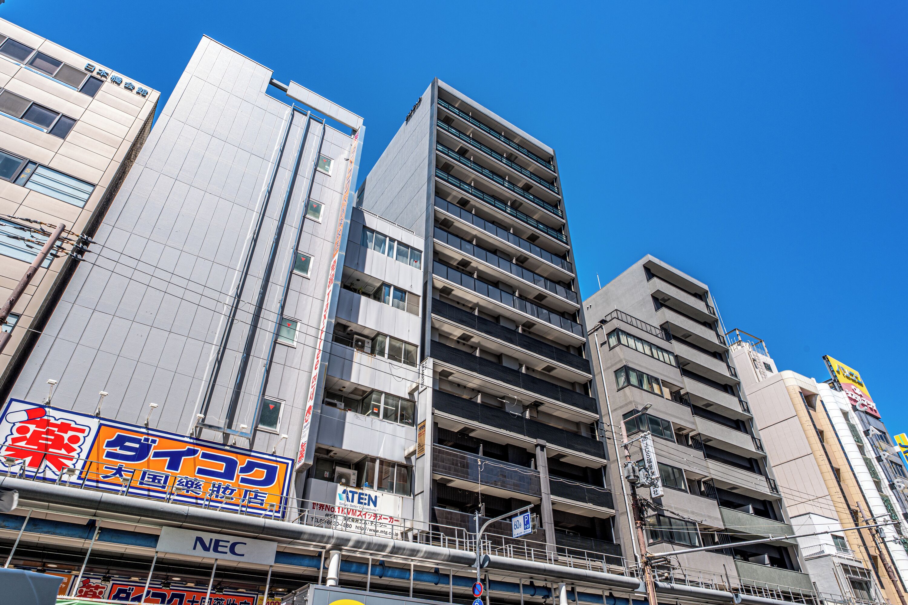 A multi-story building with commercial signage on the ground floor, including a pharmacy and a telecommunications company.