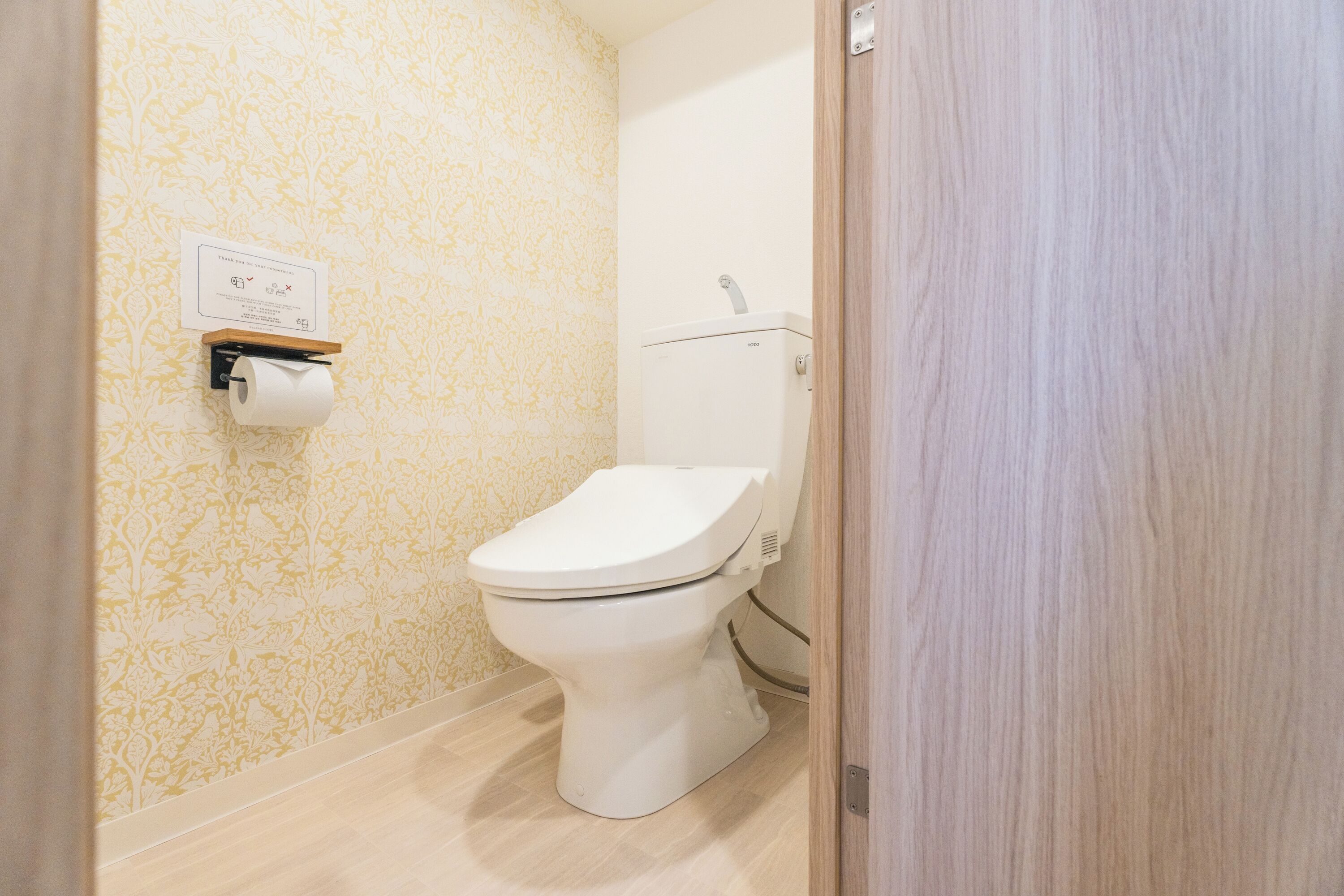 A bathroom with a toilet, a paper towel dispenser, and a wall-mounted sign.