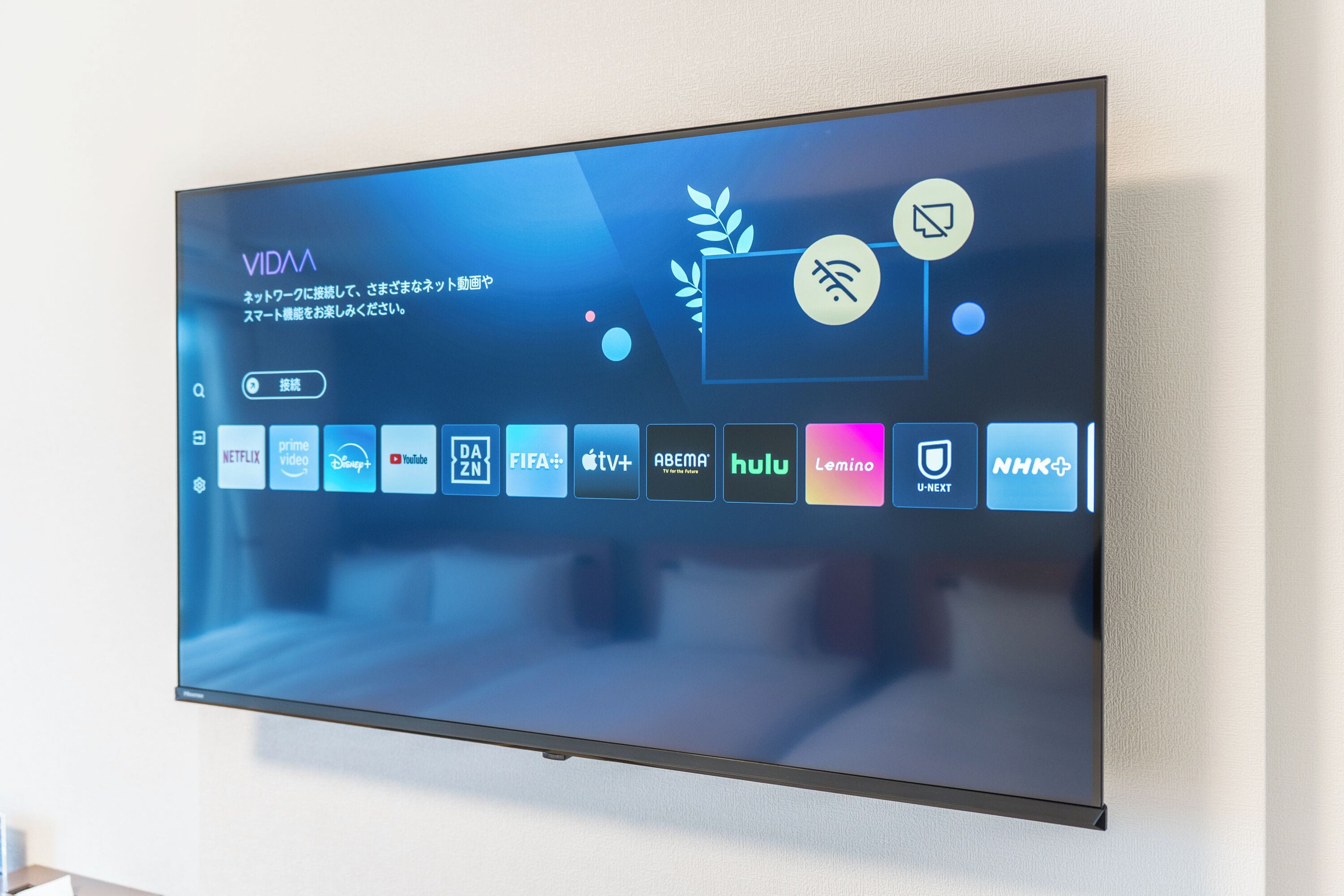 Ein Flachbildfernseher an der Wand, der eine Benutzeroberfläche mit Symbolen verschiedener Streaming-Dienste zeigt.