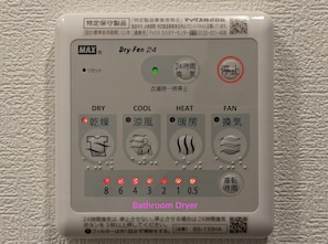 Un panneau de commande pour sèche-cheveux de salle de bain doté de plusieurs réglages, notamment pour le séchage, l’air froid, le chauffage et la ventilation.