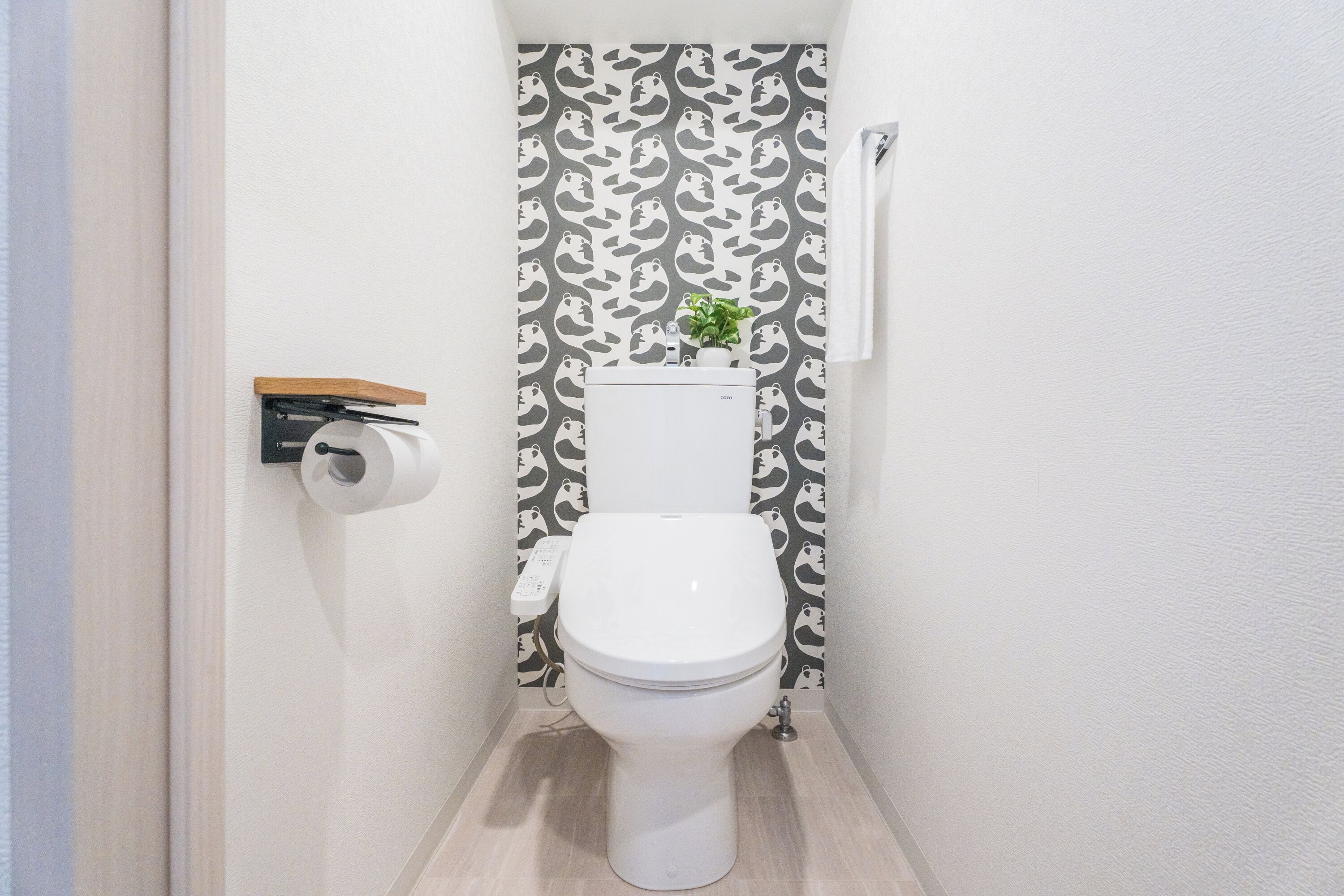 A small, narrow bathroom with a toilet, a toilet paper holder, and a towel hanging on the wall.