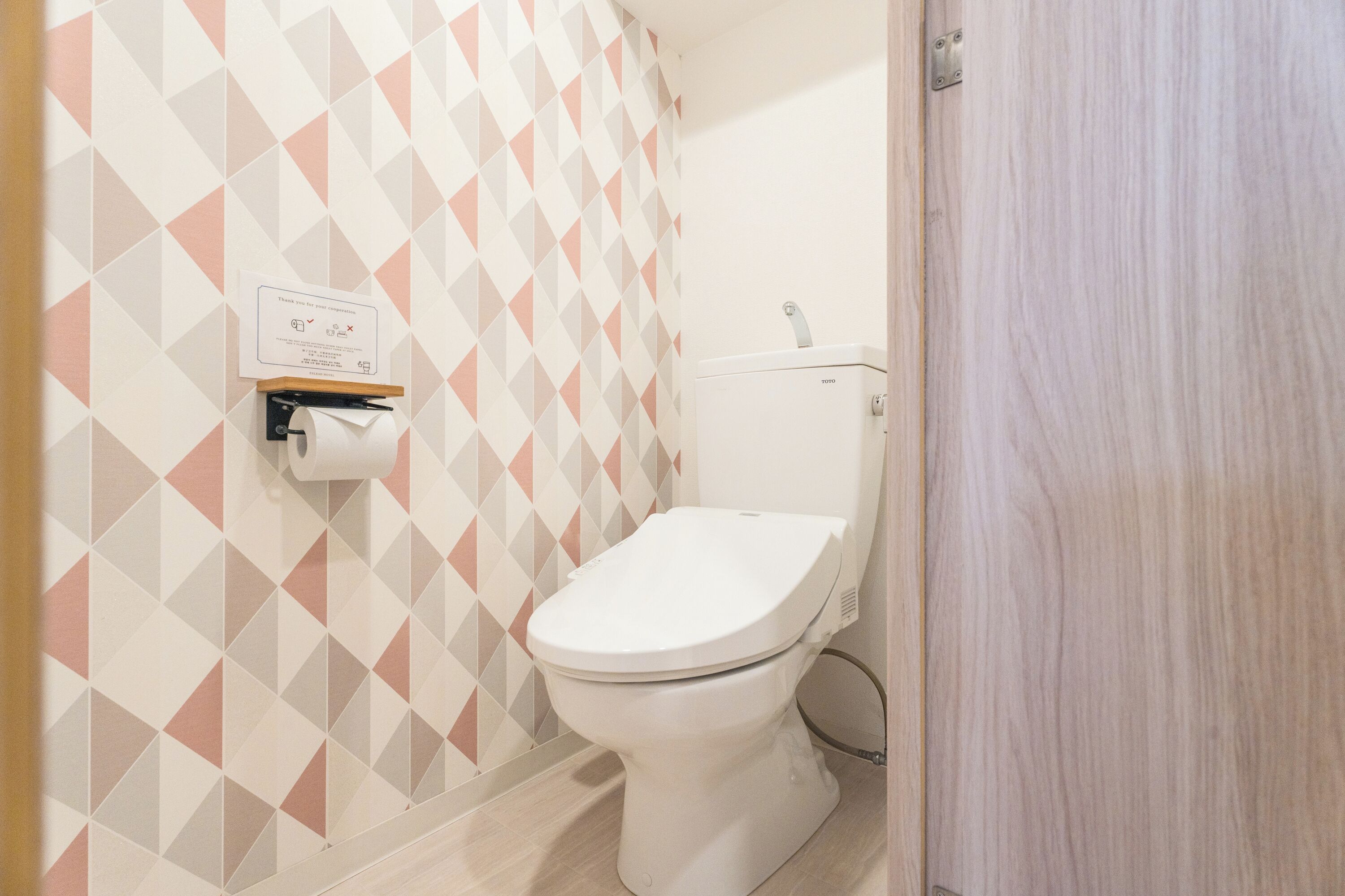 Baño pequeño y limpio con inodoro, dispensador de toallas de papel y secamanos.