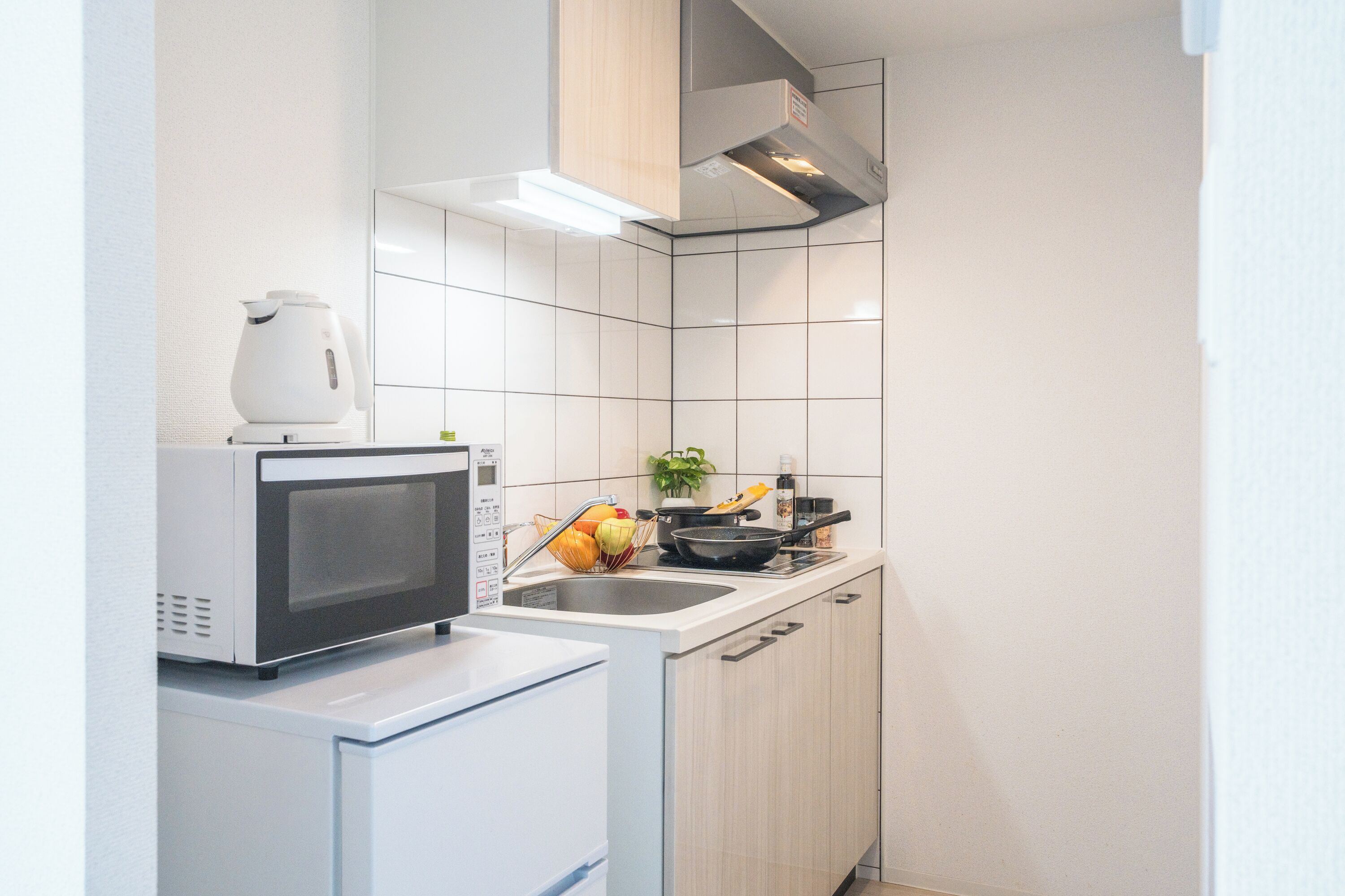 Cocina compacta con microondas, hervidor y un lavamanos pequeño.