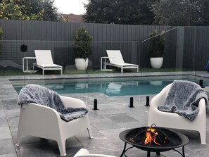 Relax by the pool surrounded by lush greenery and a warm fire pit.