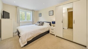 A bedroom with a bed, a wardrobe, a bedside table, and a TV on a stand. - Country cottage (Horsham)