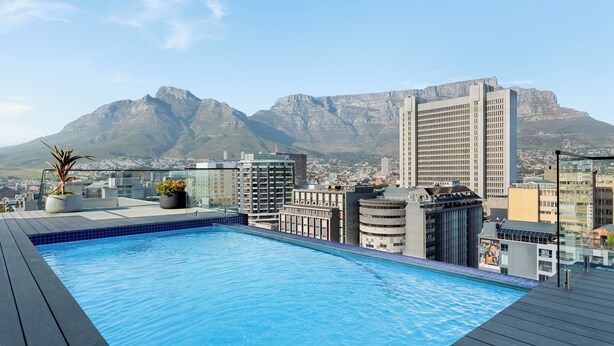 A rooftop pool with a cityscape and mountains in the background. - The Tokyo 003 (Cape Town)