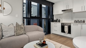 A modern kitchen with white cabinets, a built-in oven, and a window overlooking the street. - The Tokyo 003 (Cape Town)
