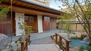 Un bâtiment de style japonais traditionnel, avec un pont de pierre menant à un bassin à carpes koï.