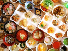 Diversos pratos dispostos sobre uma mesa de madeira, incluindo sashimi, tempura e outras especialidades da culinária japonesa.