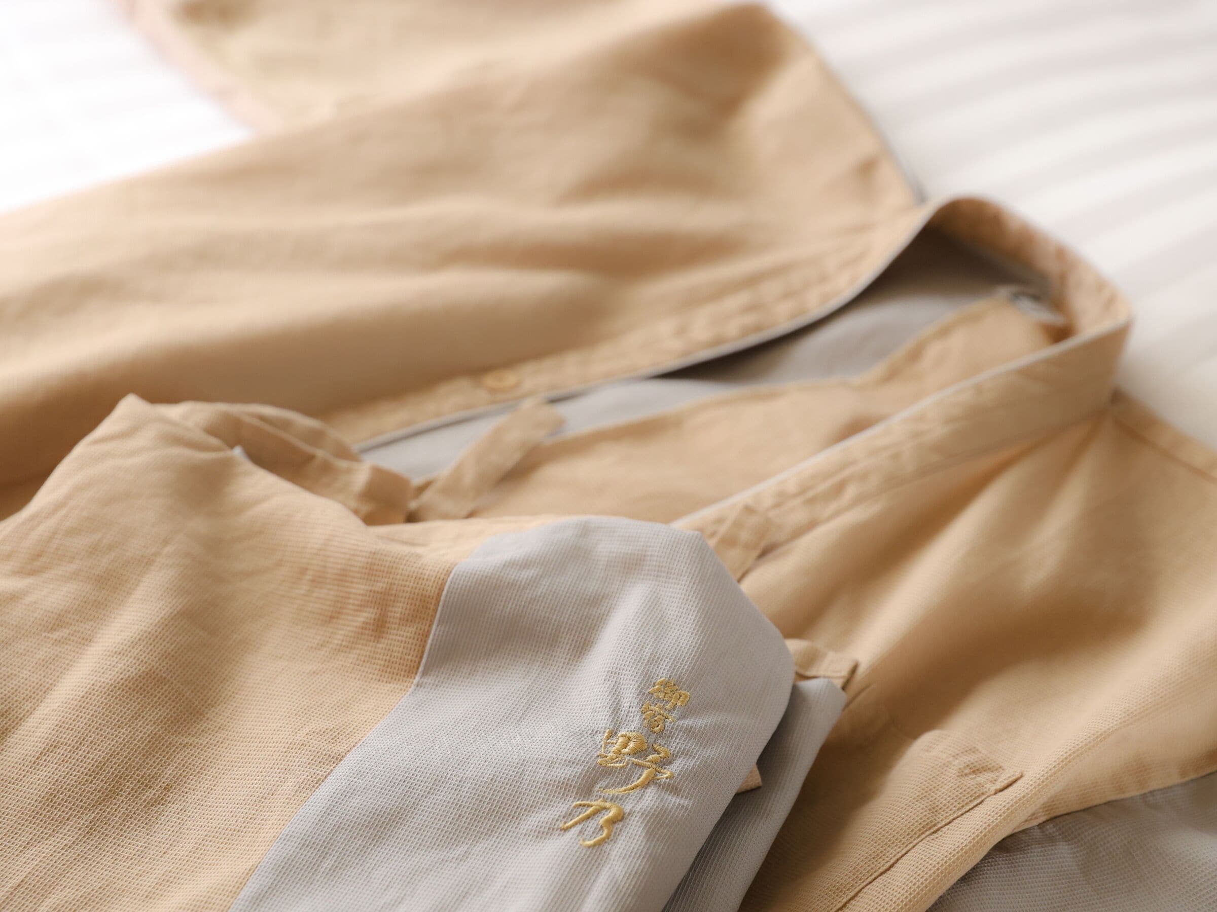 A beige garment with a white section featuring embroidered text.