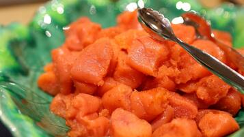 A close-up of a dish with cubed food, possibly a type of fruit or vegetable, in a green bowl with a spoon.