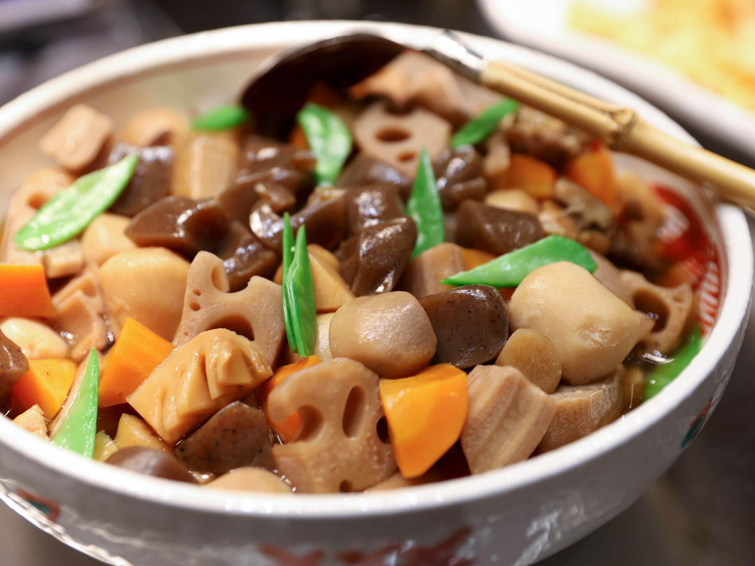 A bowl of vegetable stew with tofu and mushrooms, garnished with green leaves.