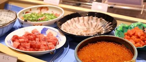 Un buffet proposant une variété de plats, notamment des sashimis, du caviar et d’autres fruits de mer.