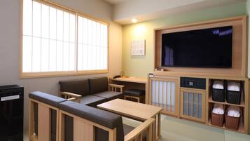 A room with a sofa, a small table, a TV, and storage baskets.