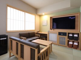 Quarto com sofá, uma mesa pequena, televisão e cestos organizadores.