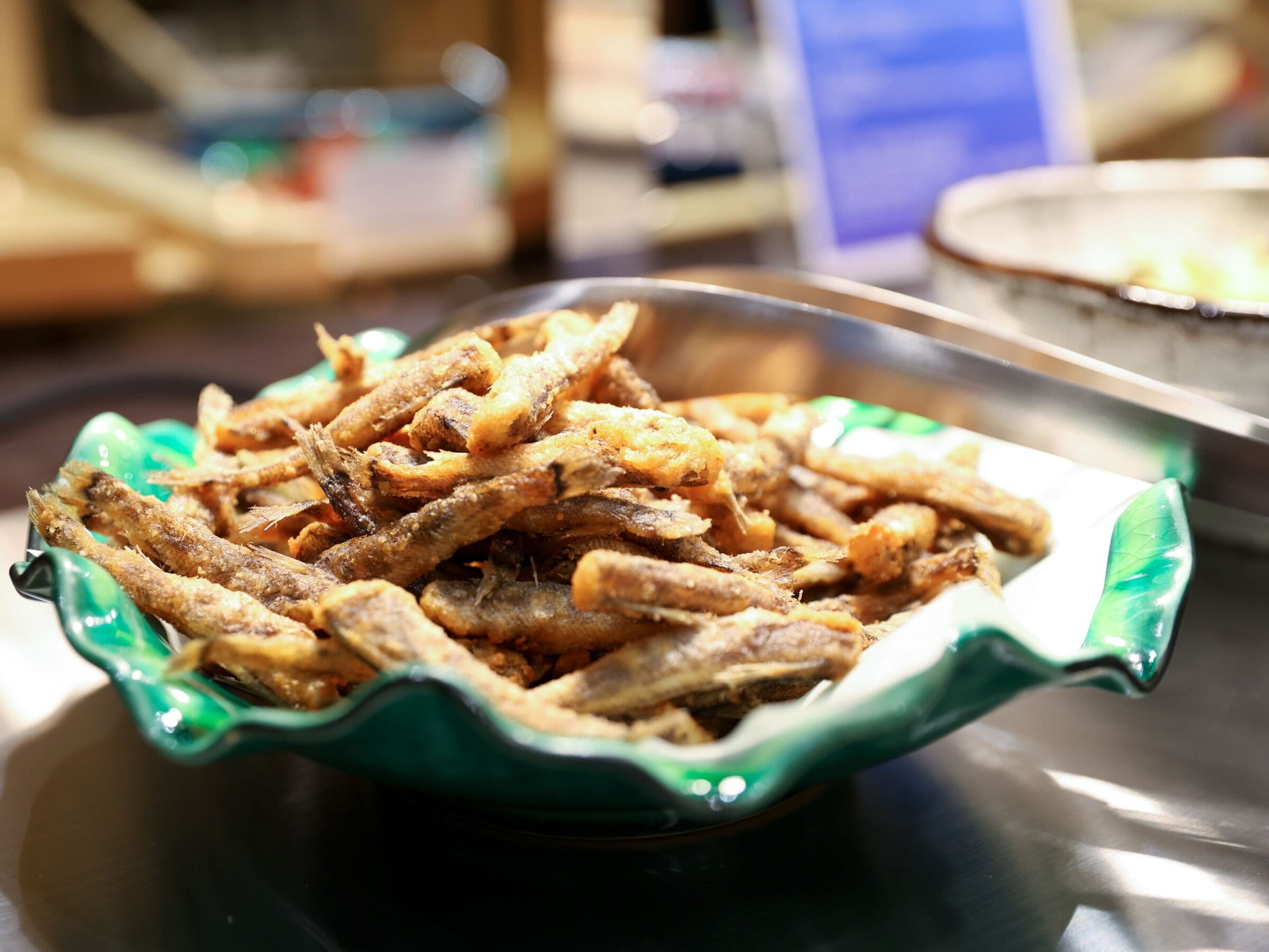 A bowl of fried fish on a table.