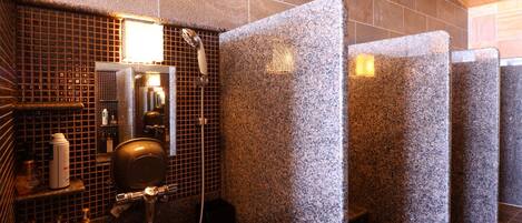 A public restroom with granite walls, a hand dryer, and a mirror.