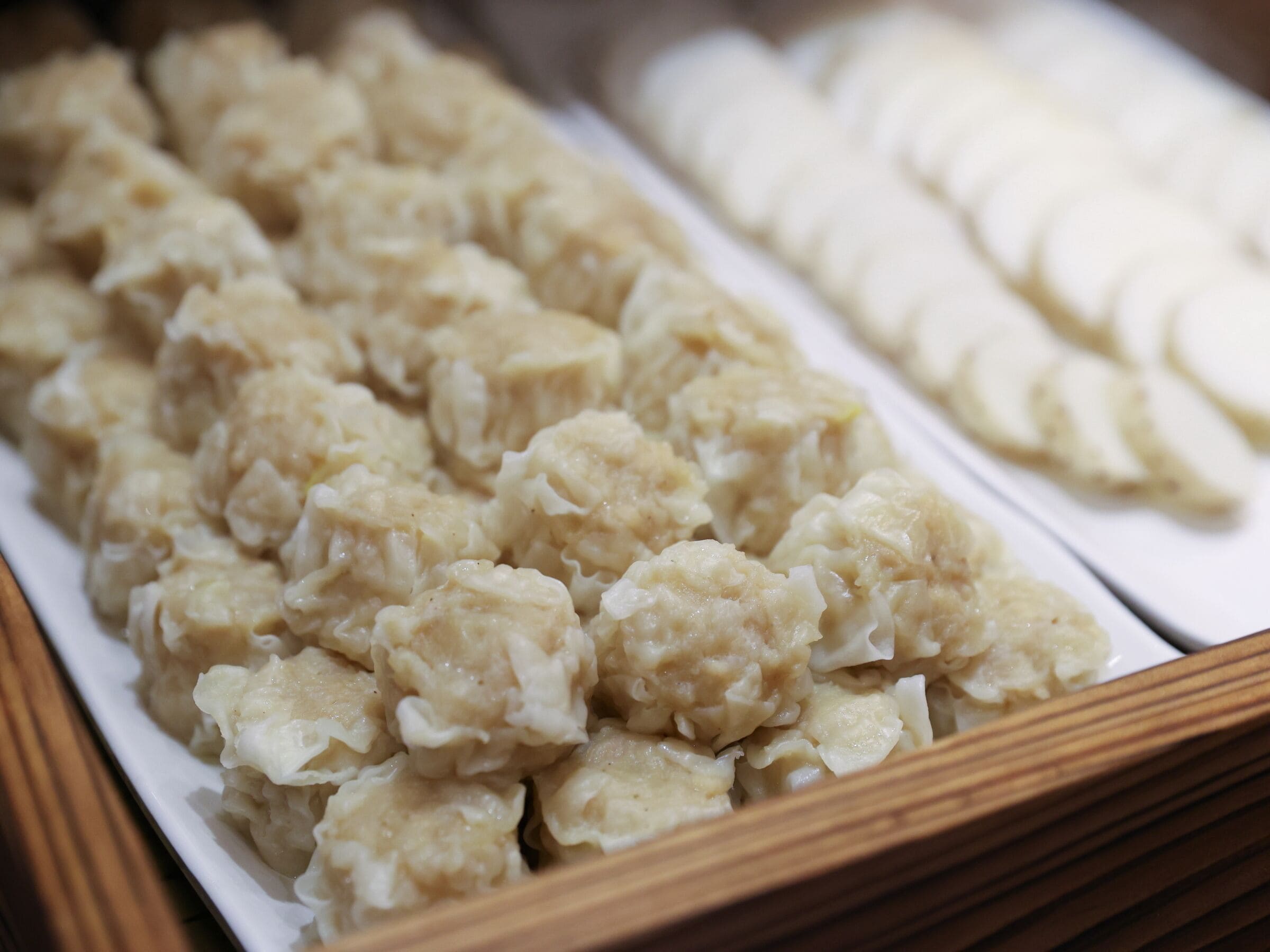 A tray of dumplings with a wooden border.