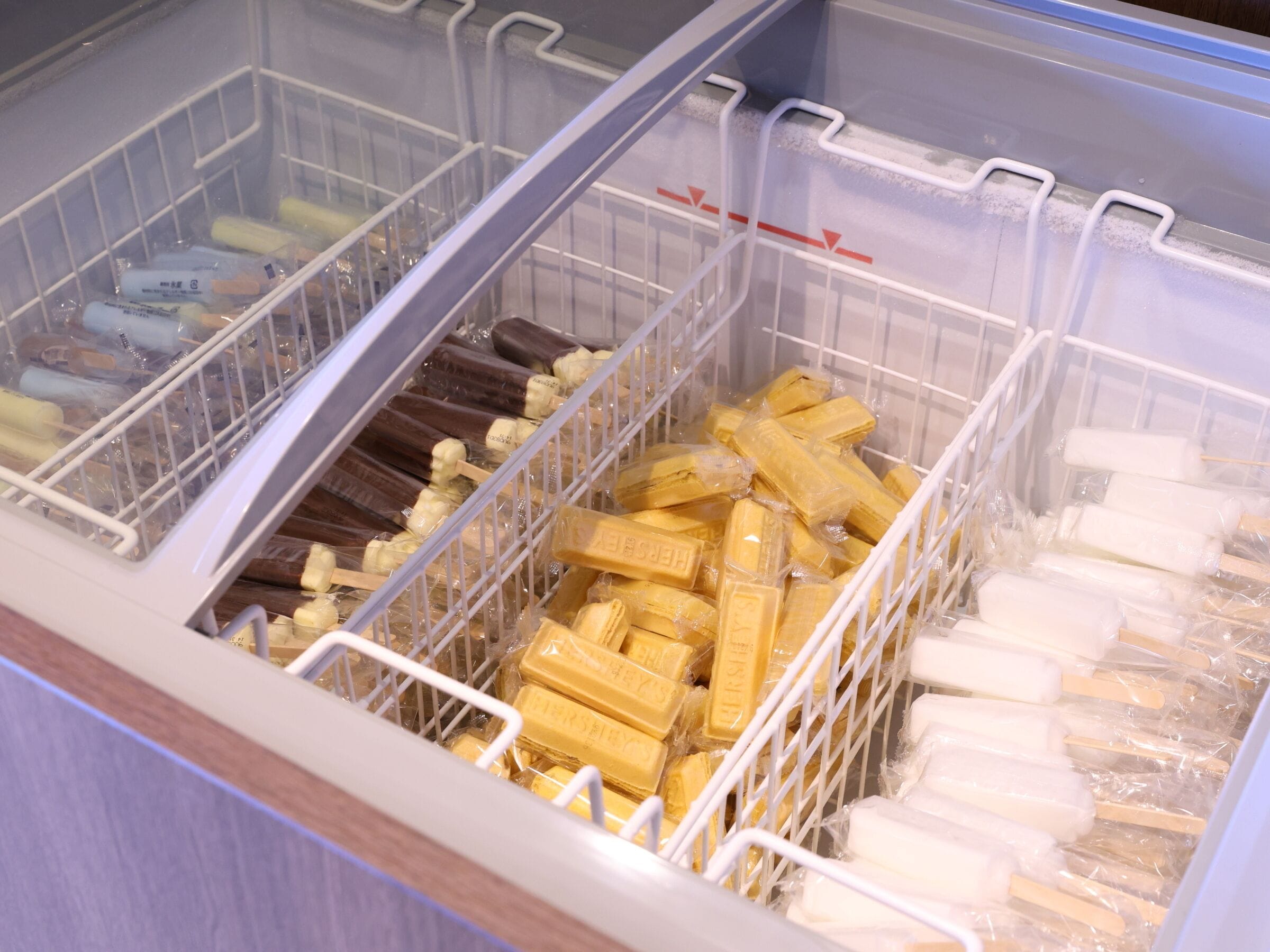 A freezer with multiple compartments containing various frozen items.