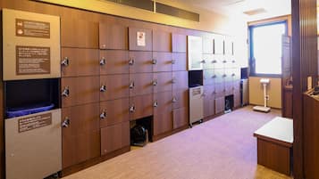 A row of wooden lockers with numbered tags, a towel collection box, and a scale.