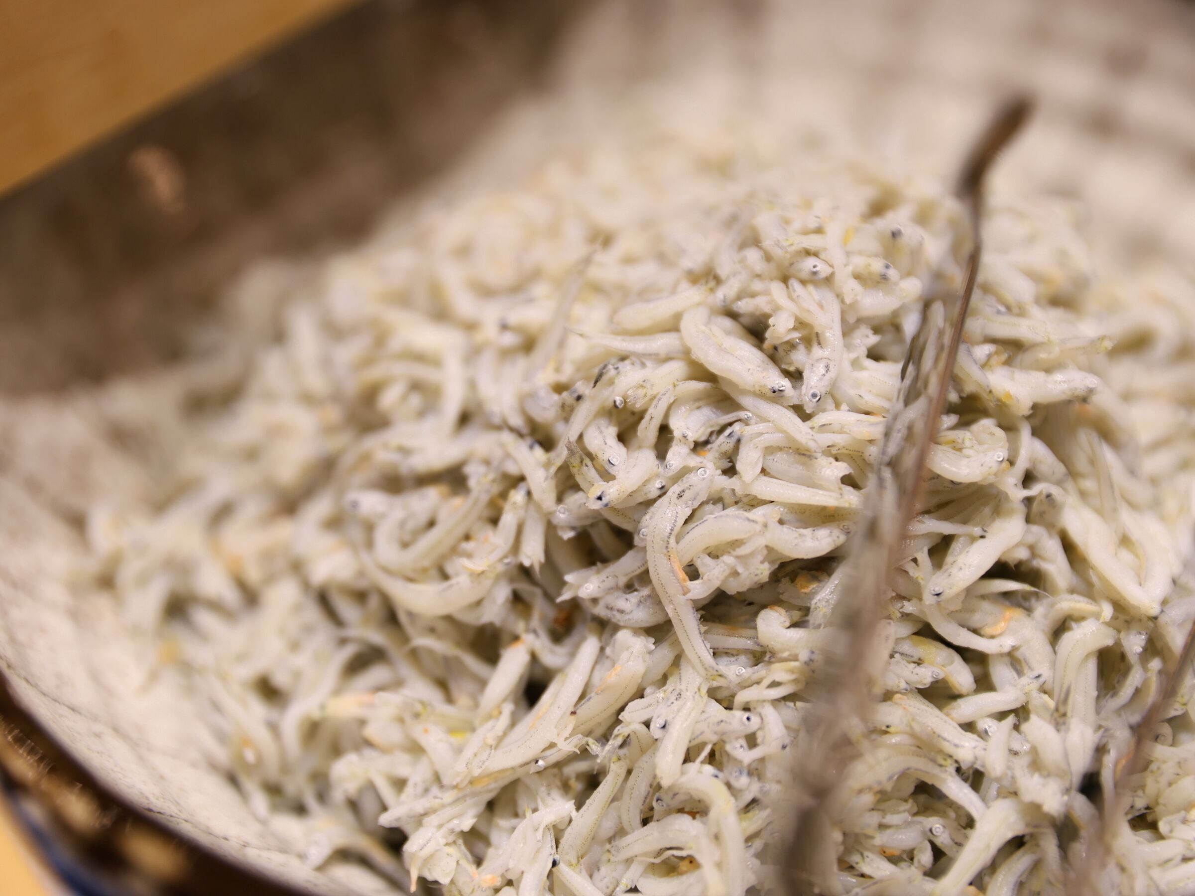 A close-up of cooked white noodles with visible seasoning, possibly in a cooking pot.