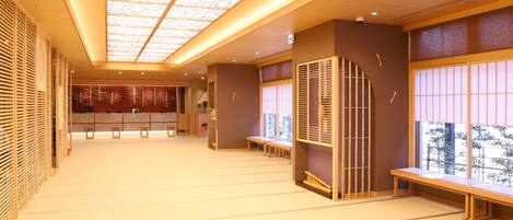 Un lobby amplio con techo alto, mostrador de recepción, zonas de estar y ventanas grandes.