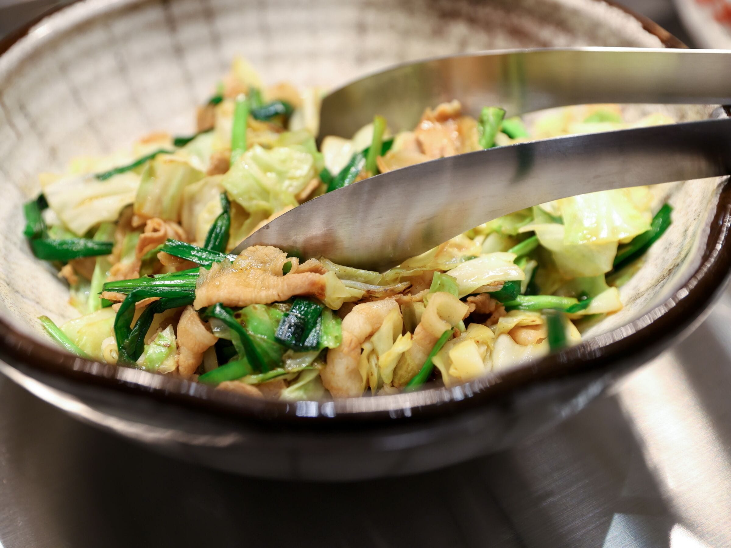 A bowl of stir-fried vegetables with a spoon.