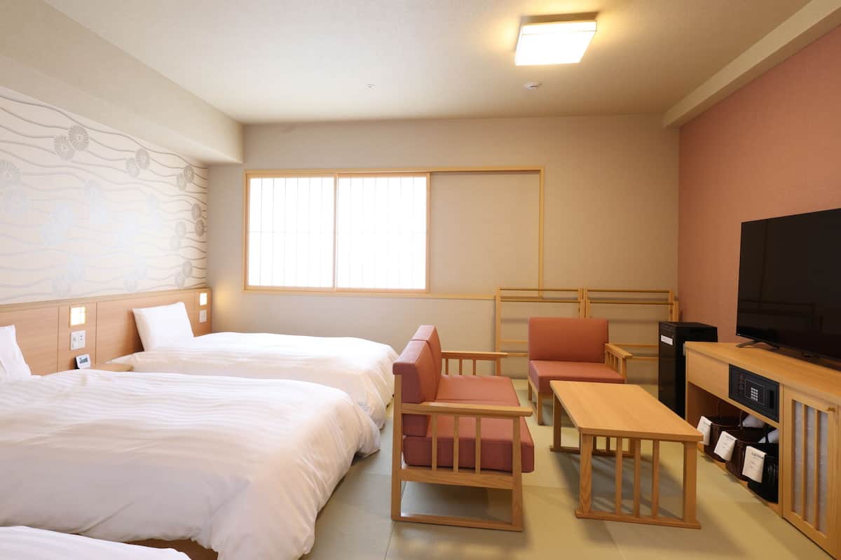 Een hotelkamer met twee bedden, een televisie, een bureau en een stoel.
