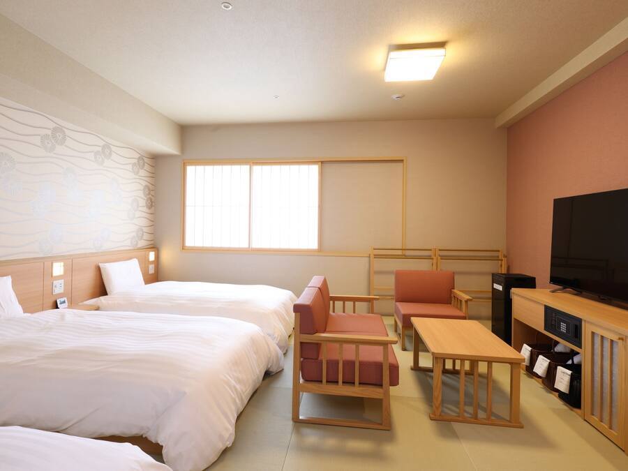A hotel room with two beds, a TV, a desk, and a chair.