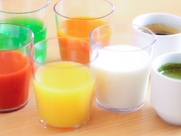 Variedad de recipientes de vidrio transparente con líquidos de colores distintos, posiblemente zumos o bebidas, sobre una superficie de madera.
