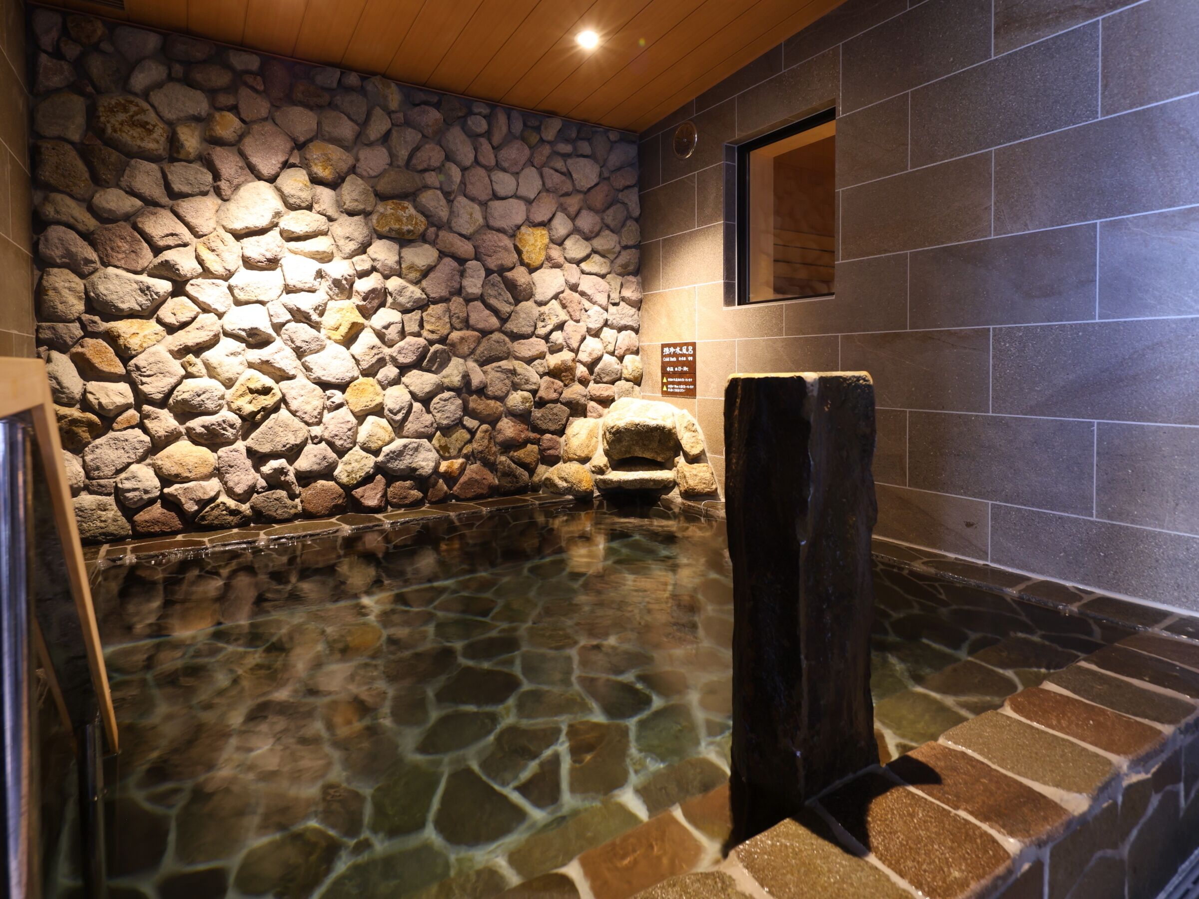 Un baño de aguas termales con paredes de piedra, techo de madera y paredes con azulejos.