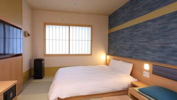 Habitación de hotel con cama, mesita de noche y un amplio ventanal.